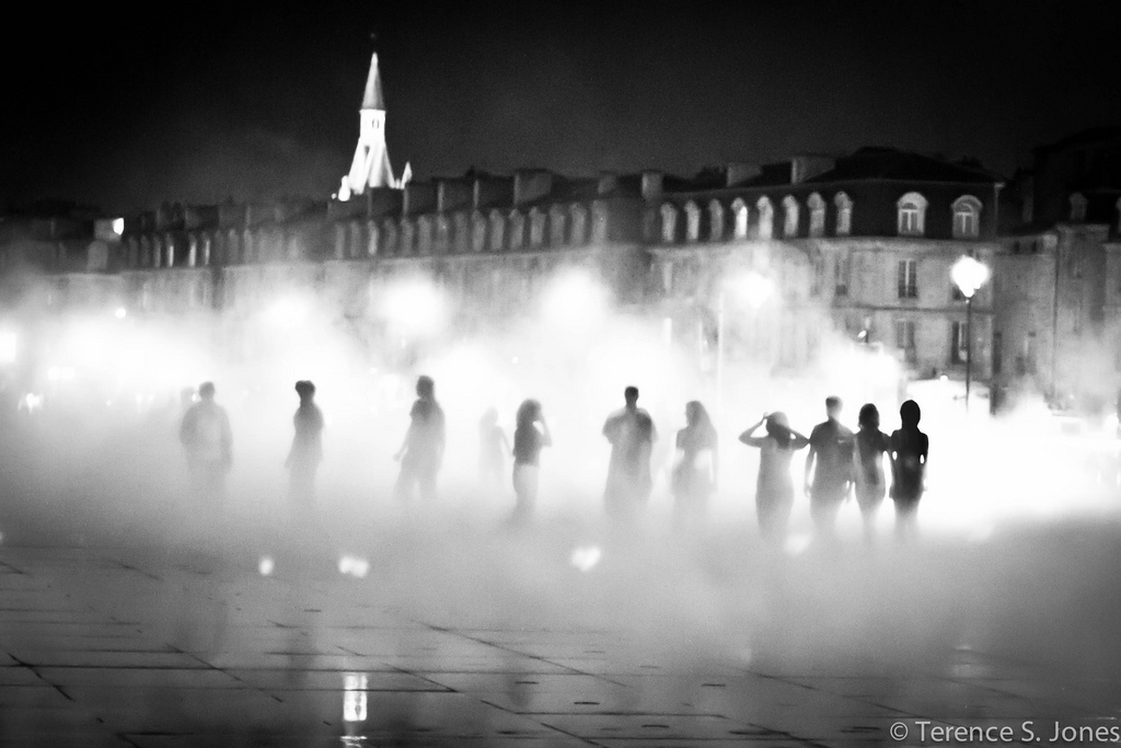 People standing in the mist of a fountain in Bordeaux, France